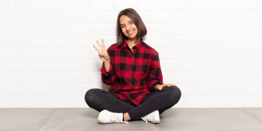 İspanyol kadın gülümsüyor ve arkadaş canlısı görünüyor. Üç ya da üç numarayı gösteriyor. Elleri önde, geri sayıyor.