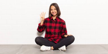 İspanyol kadın gülümsüyor ve arkadaş canlısı görünüyor. Elleri önde, geriye doğru sayıyor.