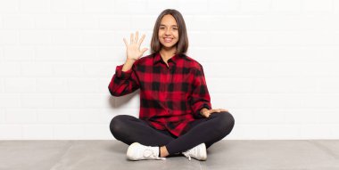 İspanyol kadın gülümsüyor ve arkadaş canlısı görünüyor, 5 ya da 5 numarayı gösteriyor, elleri önde, geri sayıyor.