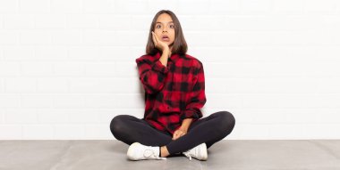 İspanyol kadın şok ve inançsızlıkla ağzı açık, elleri yanak ve kolları çaprazlanmış, sersemlemiş ve şaşırmış hissediyor.