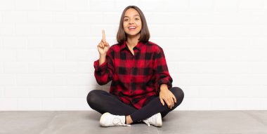 İspanyol kadın mutlu bir şekilde gülümsüyor, tek eliyle uzayı işaret ediyor.