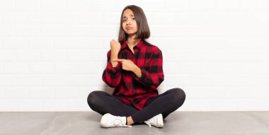 İspanyol kadın sabırsız ve kızgın görünüyor, saati gösteriyor, dakiklik istiyor, zamanında gelmek istiyor.