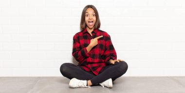 İspanyol kadın heyecanlı ve şaşırmış görünüyor. Yana ve yukarı doğru uzayı gösteriyor.