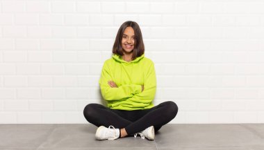 İspanyol kadın mutlu, gururlu ve tatmin olmuş görünüyor. Kollarını kavuşturup gülümsüyor.