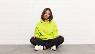 İspanyol kadın pozitif ve kendinden emin gülümsüyor. Tatmin olmuş, arkadaş canlısı ve mutlu görünüyor.