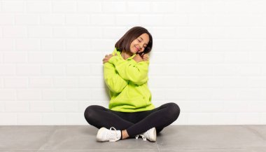 Hispanik kadın aşık, gülümseyen, sarılan ve kendine sarılan, bekar, bencil ve benmerkezci.