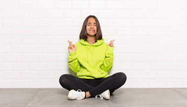 İspanyol kadın gülümsüyor ve endişeyle iki parmağını çapraz yapıyor. Endişeli ve iyi şanslar diliyor.