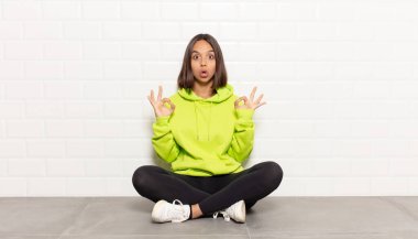 İspanyol kadın şok olmuş, şaşırmış ve şaşırmış hissediyor. Onaylıyor. İki eliyle işaret veriyor.