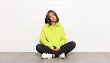 hispanic woman feeling puzzled and confused, with a dumb, stunned expression looking at something unexpected