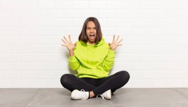 İspanyol kadın panik ya da öfke içinde bağırıyor, şok olmuş, korkmuş ya da öfkeli, elleri başının yanında.