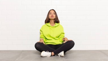 Tatlı, eğlenceli, mutlu, sevimli bir yüz ifadesiyle dudaklarını birbirine bastıran İspanyol kadın öpücük yolluyor.