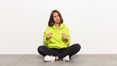 İspanyol kadın şaşkın ve şaşkın bir bakışla kendini işaret ediyor. Seçildiğine şaşırmış ve şaşırmış.