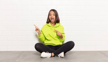 İspanyol kadın kendini neşeli ve şaşırmış hissediyor. Şok olmuş bir ifadeyle gülümsüyor ve bir tarafı işaret ediyor.