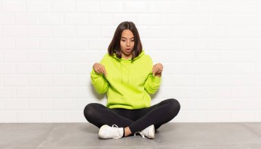 İspanyol kadın şok olmuş, ağzı açık ve şaşırmış hissediyor. İnançsızlık ve şaşkınlık içinde bakıyor ve onu işaret ediyor.