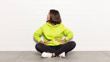 Hispanik kadın kafası karışık ya da dolu ya da şüphe ve soru dolu, merak ediyor, elleri kalçasında, dikiz aynasından