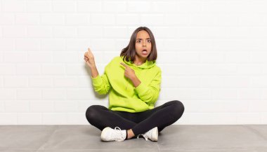 İspanyol kadın şaşkın ve şaşırmış hissediyor. Kenardaki fotokopi alanını işaret ediyor. Şaşırmış, ağzı açık bir bakışla.