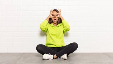 İspanyol kadın şaşkın, şaşkın ve şaşırmış hissediyor, elinde şaşkın, inançsız bir bakışla gözlük tutuyor.