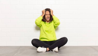 İspanyol kadın kendini stresli ve hayal kırıklığına uğramış hissediyor, elele tutuşuyor, yorgun, mutsuz ve migren ağrısı çekiyor.