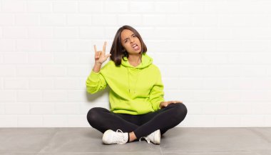 İspanyol kadın kendini mutlu, eğlenceli, kendinden emin, pozitif ve asi hissediyor, elle rock veya heavy metal işareti yapıyor.