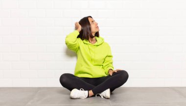 İspanyol kadın bilgisiz ve kafası karışık, bir çözüm düşünüyor, eli kalçasında, diğeri kafasında, dikiz aynasından.