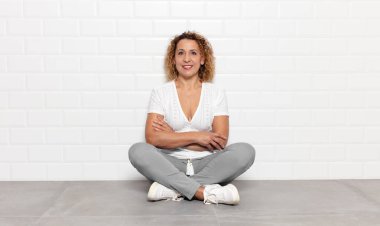 Kollarını kavuşturup kameraya gülümseyen orta yaşlı bir kadın ve mutlu, kendinden emin, tatmin olmuş bir ifade.