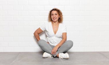 Orta yaşlı bir kadın mutlu bir şekilde gülümsüyor. Kendine güvenen, olumlu, gururlu ve arkadaş canlısı bir tavırla.