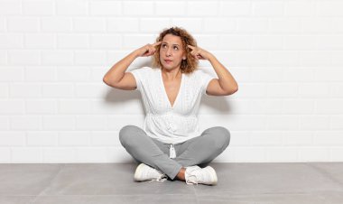 Orta yaşlı bir kadın kafası karışık ya da şüpheci, bir fikre odaklanmış, çok düşünüyor, kenarda boşluklar arıyor.