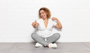 Orta yaşlı bir kadın gururlu, tasasız, kendinden emin ve mutlu, olumlu gülümsüyor.