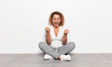 Orta yaşlı bir kadın sinirli, sinirli, kızgın bakışlar ve sıkı yumruklarla bağırıyor. Öfkeli hissediyor.