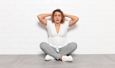 Orta yaşlı bir kadın stresli, endişeli, endişeli ya da korkmuş, elleri başının üstünde, hata yaptığında panikliyor.