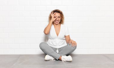 Orta yaşlı bir kadın mutlu bir şekilde gülümsüyor, şaka yapıyor ve gözetleme deliğinden bakıyor, sırları gözetliyor.