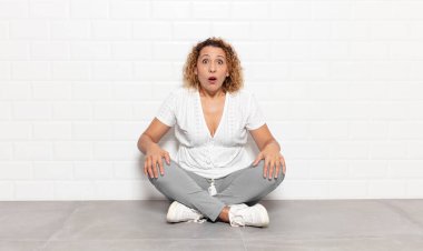 Orta yaşlı bir kadın şok olmuş ya da şaşırmış görünüyor, ağzı açık bir şekilde 