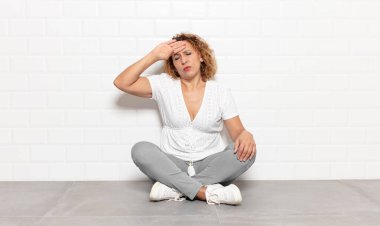 Orta yaşlı kadın stresli, yorgun ve hayal kırıklığına uğramış görünüyor, alnından ter damlıyor, umutsuz ve bitkin hissediyor.