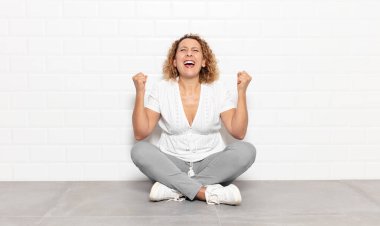 Orta yaşlı kadın son derece mutlu ve şaşırmış görünüyor, başarıyı kutluyor, bağırıyor ve zıplıyor.