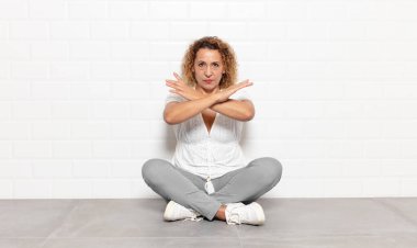 Orta yaşlı bir kadın senin tavırlarından rahatsız ve bıkkın görünüyor. Yeter artık! Eller önde çapraz, durmanı söylüyor.