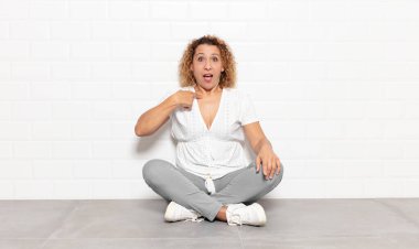 Orta yaşlı kadın mutlu, gururlu ve şaşırmış görünüyor, neşeli bir şekilde kendini gösteriyor, kendinden emin ve kibirli hissediyor.