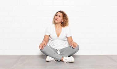 Orta yaşlı kadın şaşkın ve şaşkın görünüyor, merak ediyor veya bir sorunu çözmeye çalışıyor veya düşünüyor.