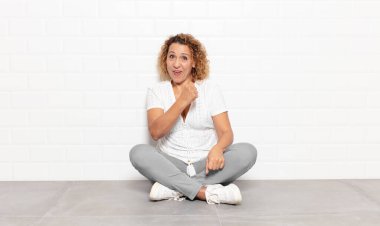 Orta yaşlı bir kadın mutlu, pozitif ve başarılı hissediyor, bir meydan okumayla karşılaştığında motive oluyor veya iyi sonuçları kutluyor.