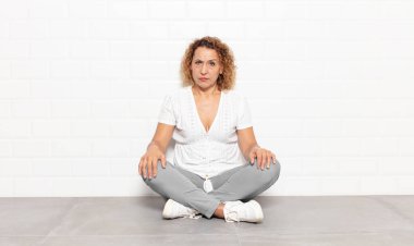 Orta yaşlı bir kadın kafası karışık ve kuşkulu, merak ediyor ya da karar vermeye çalışıyor.