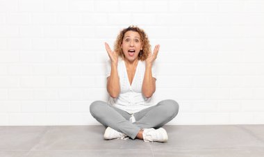 Orta yaşlı bir kadın beklenmedik bir sürpriz yüzünden şaşkın, heyecanlı, gülen, şaşkın ve mutlu hissediyor.