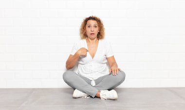 Orta yaşlı bir kadın şaşkın, şaşkın ve güvensiz hissediyor. Kendini gösterip kim olduğunu soruyor, ben mi??