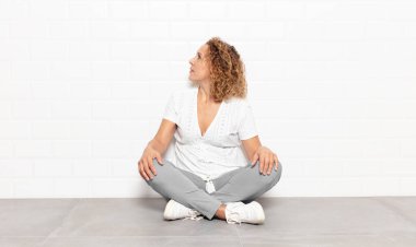 Orta yaşlı bir kadın kafası karışık ya da dolgun ya da şüphe ve soru dolu, merak ediyor, elleri kalçasında, dikiz aynasından.