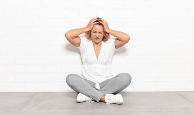 Orta yaşlı bir kadın kendini stresli ve hayal kırıklığına uğramış hissediyor. Yumruk yumruğa, yorgun, mutsuz ve migren ağrısı çekiyor.