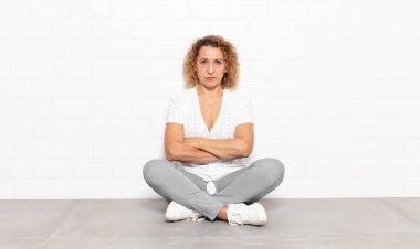 Orta yaşlı bir kadın mutsuz ve hayal kırıklığına uğramış, ciddi görünüyor, kızgın ve kollarını kavuşturmuş.