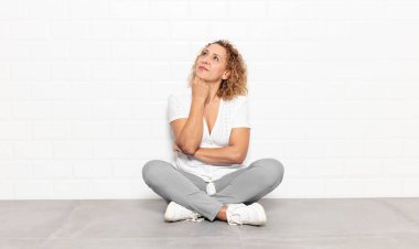 Orta yaşlı bir kadın düşünceli, meraklı ya da hayal kuruyor, hayal kuruyor ve uzayı kopyalamak için yukarı bakıyor.