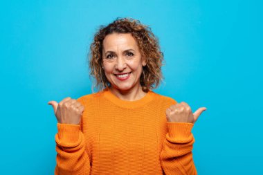 Orta yaşlı bir kadın neşeyle gülümsüyor ve mutlu görünüyor, kaygısız ve pozitif hissediyor.