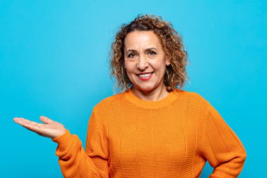 Orta yaşlı kadın gülümsüyor, kendinden emin, başarılı ve mutlu hissediyor, fotokopi alanında fikir veya konsept gösteriyor.