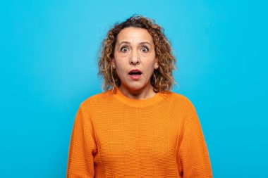 Orta yaşlı bir kadın şok olmuş ya da şaşırmış görünüyor, ağzı açık bir şekilde 