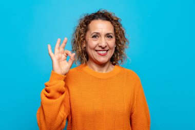 Orta yaşlı bir kadın mutlu, rahat ve tatmin olmuş hissediyor. Onayını iyi bir hareketle gösteriyor.