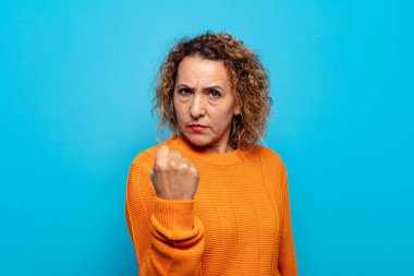 Orta yaşlı bir kadın kızgın, sinirli, asi ve agresif orta parmağını sallayarak karşılık veriyor.